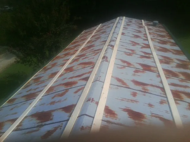 Rusted metal roof panels with new wood purlins before replacement — Storm Damage Roof Repair in Ada by Roofing Brothers