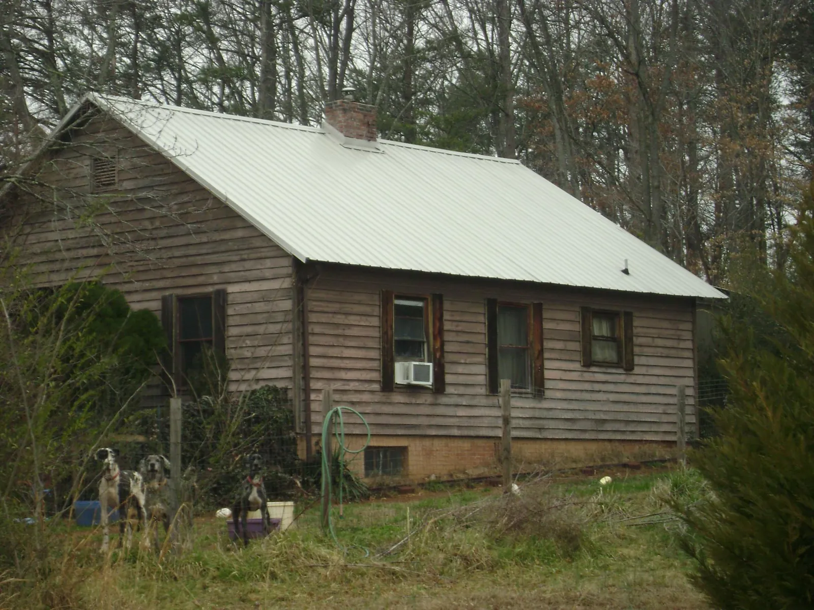White metal roof on an old wood sided farmhouse, from a Metal Roof Installation job in Ada